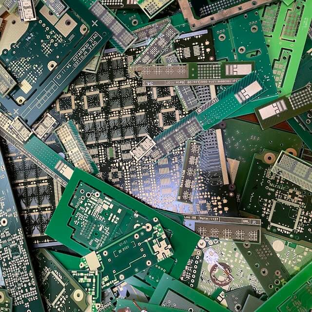 Pile of assorted green printed circuit board scraps with visible copper tracings
