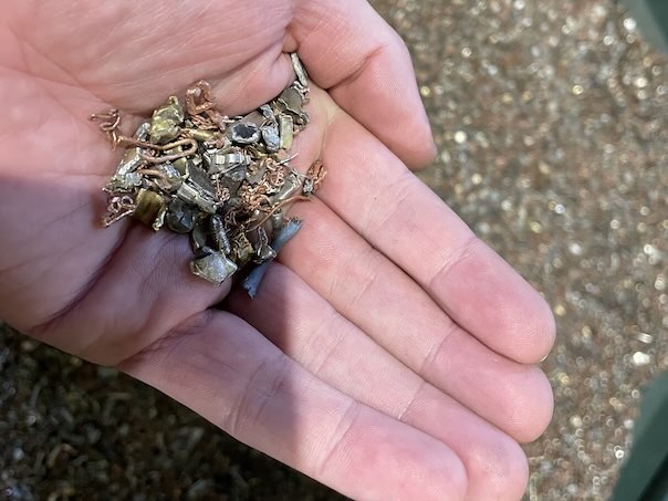 An open hand holding a small amount of small metal parts like brass or copper