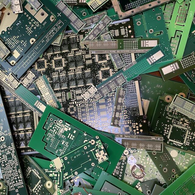 Pile of assorted green printed circuit board scraps with visible copper tracings